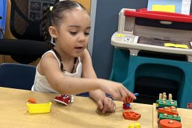 Preschool girl points to a stacking toy