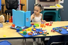 Preschool girl at a table filled with toys