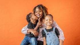 Mom hugs her two children. The boy kisses her cheek.